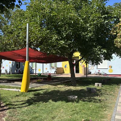 Bild vergr&ouml;&szlig;ern: Der gro&szlig;e Baum spendet viel Schatten auch au&szlig;erhalb des Sonnensegels &uuml;ber dem Sandkasten.
